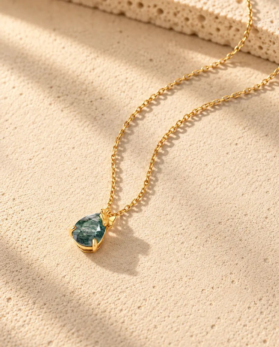 Collar de Ágata Musgosa en Forma de Gota en Plata 925 Chapada en Oro - visto en ángulo sobre una superficie clara con textura