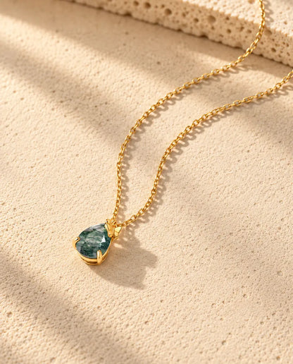 Collar de Ágata Musgosa en Forma de Gota en Plata 925 Chapada en Oro - visto en ángulo sobre una superficie clara con textura