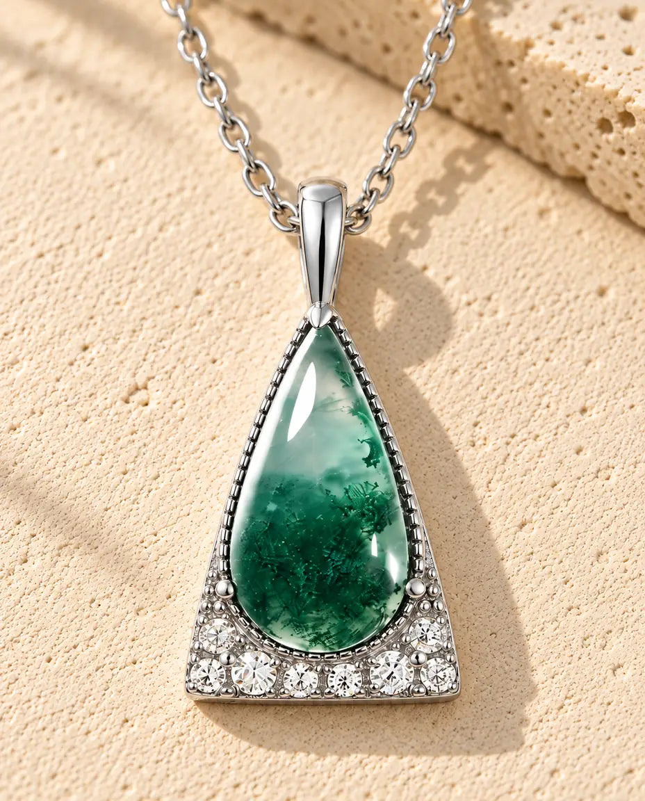 Collar de Ágata Musgosa Triángulo en Plata 925 - sobre una superficie clara con textura junto a un bloque de travertino