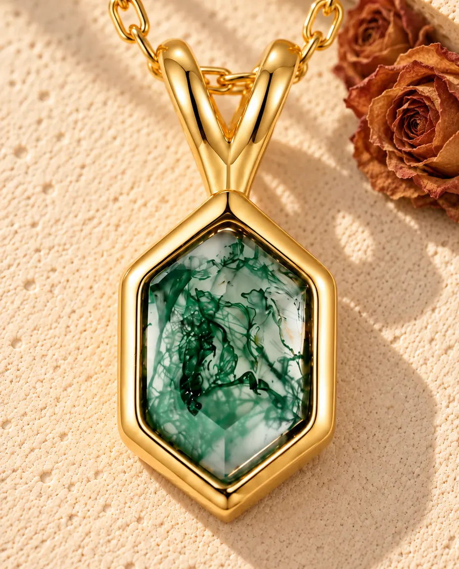 Collar de Ágata Musgosa Hexagonal en Plata 925 Chapada en Oro - sobre una superficie clara con textura junto a un bloque de travertino
