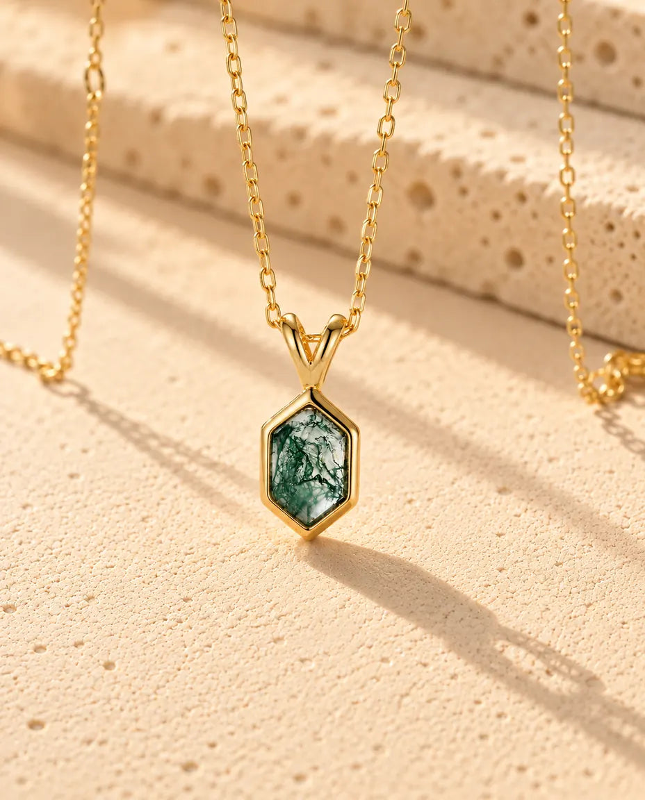 Collar de Ágata Musgosa Hexagonal en Plata 925 Chapada en Oro - visto en ángulo sobre una superficie clara con textura