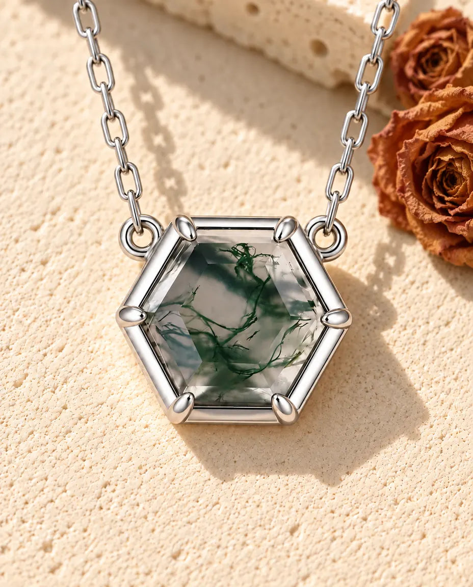 Collar de Ágata Musgosa Hexagonal en Plata 925 - sobre una superficie clara con textura junto a un bloque de travertino