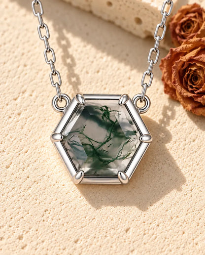 Collar de Ágata Musgosa Hexagonal en Plata 925 - sobre una superficie clara con textura junto a un bloque de travertino