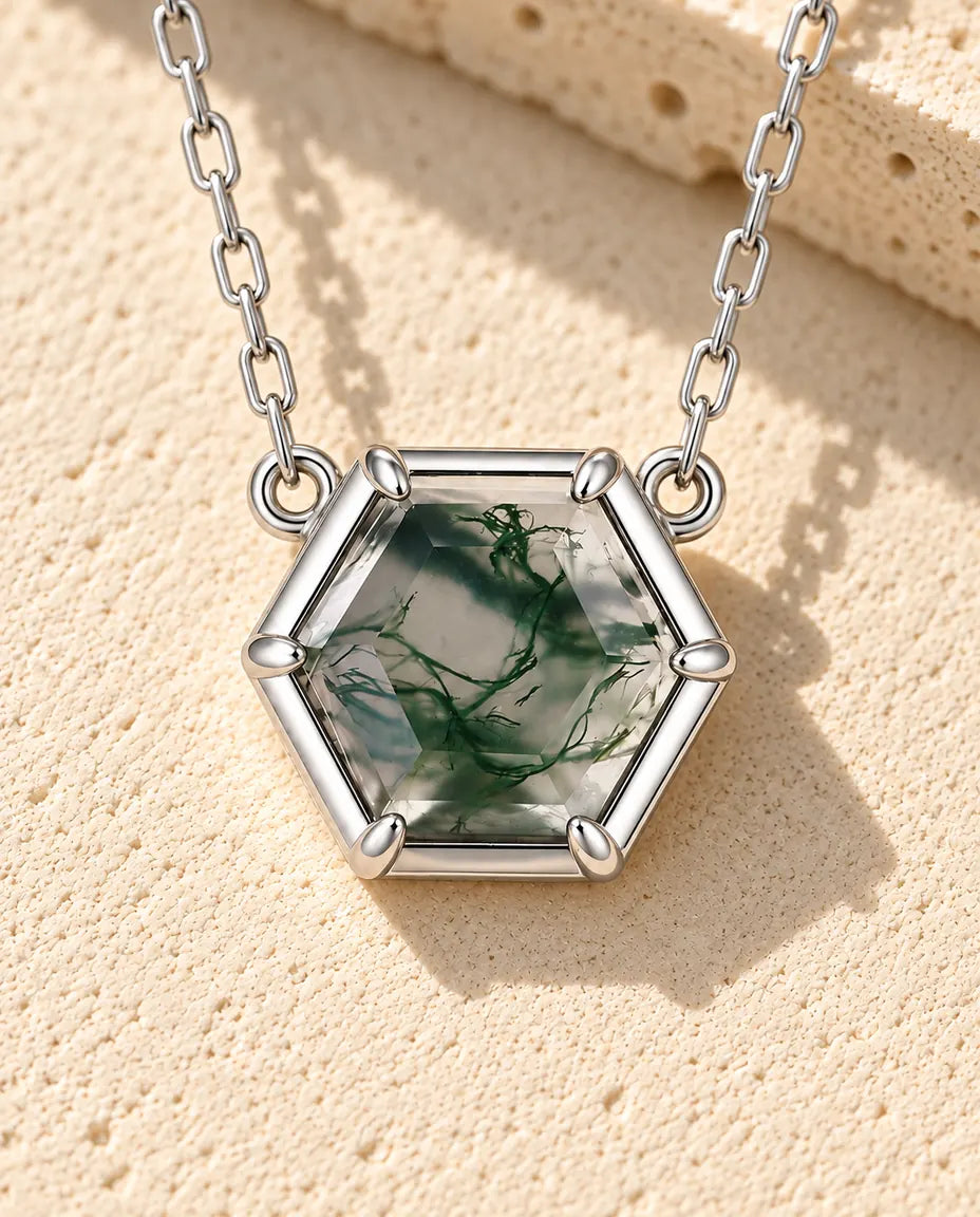 Collar de Ágata Musgosa Hexagonal en Plata 925 - sobre una superficie clara con textura junto a un bloque de travertino