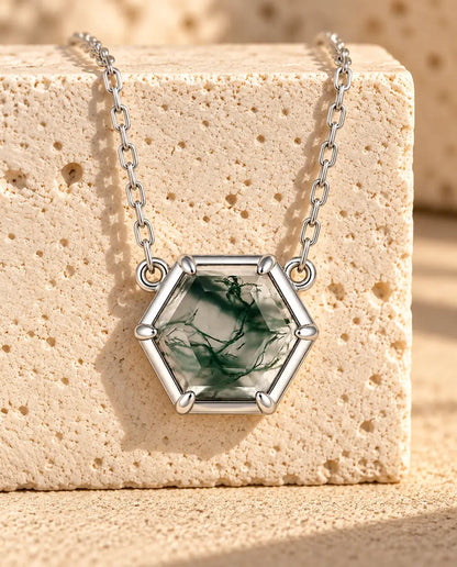 Collar de Ágata Musgosa Hexagonal en Plata 925 - colgado sobre un bloque de travertino