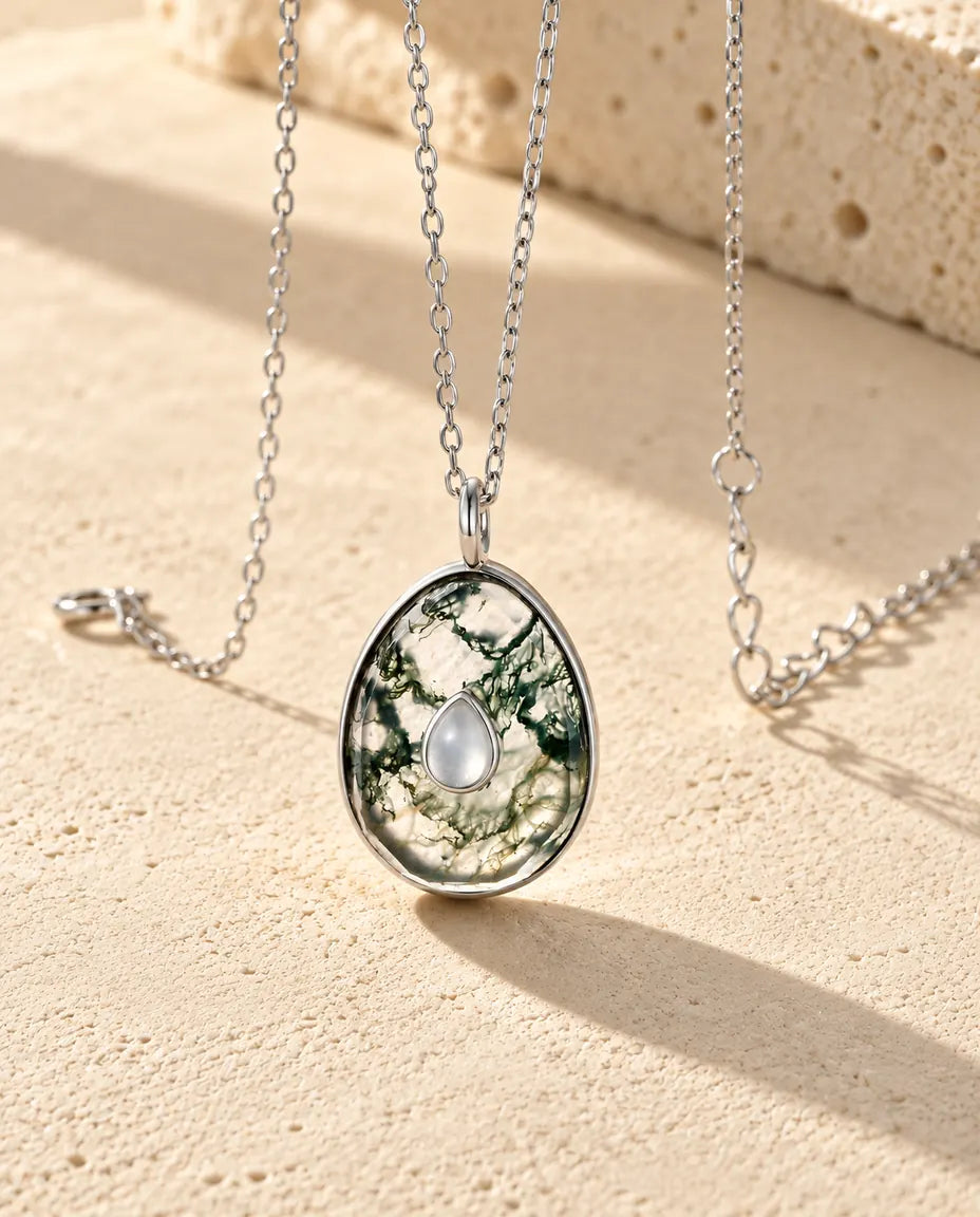 Collar de Ágata Musgosa en Forma de Huevo en Plata 925 - visto en ángulo sobre una superficie clara con textura