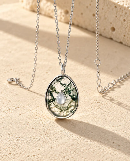 Collar de Ágata Musgosa en Forma de Huevo en Plata 925 - visto en ángulo sobre una superficie clara con textura