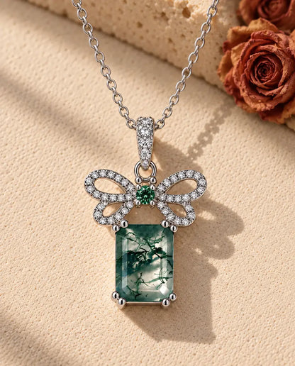 Collar de Ágata Musgosa Lazo en Plata 925 - sobre una superficie clara con textura junto a un bloque de travertino