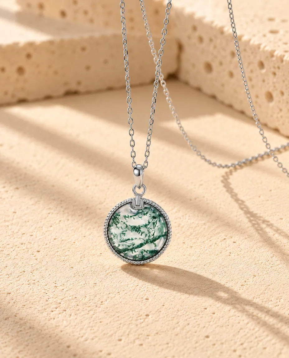 Collar de Ágata Musgosa con Colgante Redondo en Plata 925 - visto en ángulo sobre una superficie clara con textura