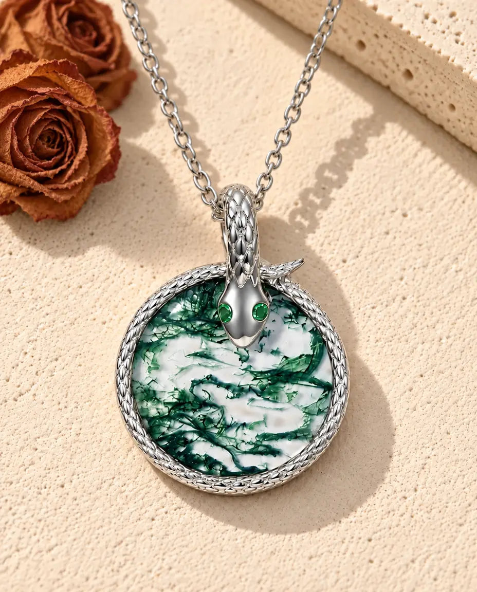 Collar de Ágata Musgosa Serpiente en Plata 925 - sobre una superficie clara con textura junto a un bloque de travertino