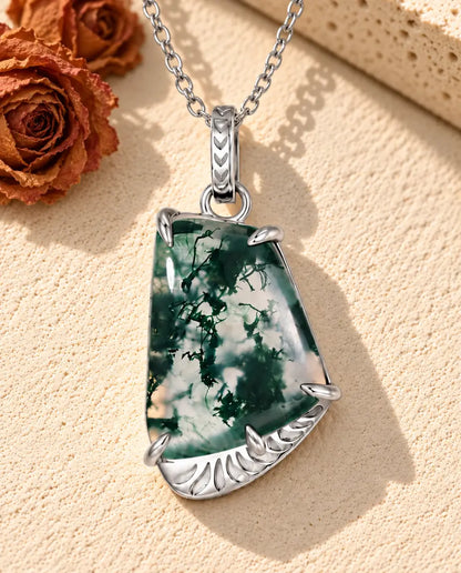Collar de Ágata Musgosa Forma Libre en Plata 925 - sobre una superficie clara con textura junto a un bloque de travertino