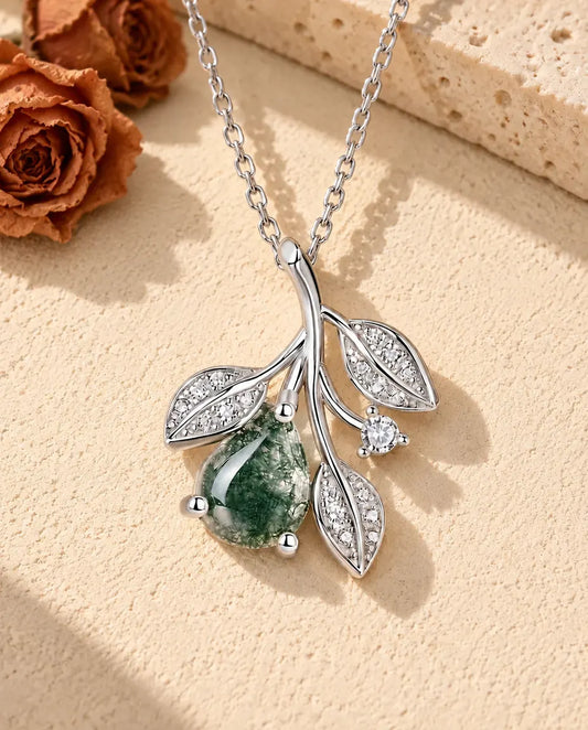 Collar de Ágata Musgosa con Hojas en Plata 925 - sobre una superficie clara con textura junto a un bloque de travertino