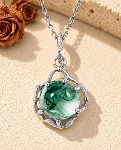 Collar de Ágata Musgosa Redonda en Plata 925 - sobre una superficie clara con textura junto a un bloque de travertino