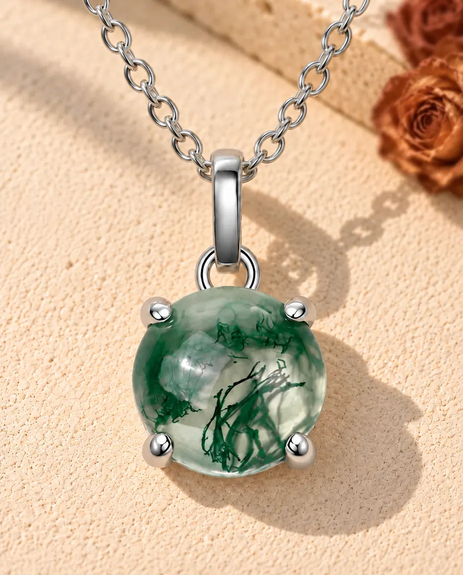 Collar de Ágata Musgosa Redonda en Plata 925 - sobre una superficie clara con textura junto a un bloque de travertino