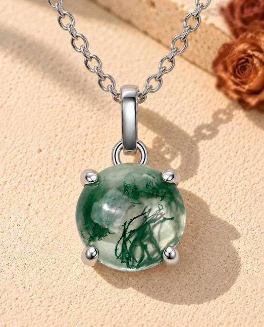 Collar de Ágata Musgosa Redonda en Plata 925 - sobre una superficie clara con textura junto a un bloque de travertino