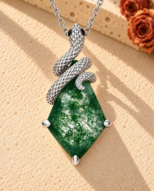 Collar de Ágata Musgosa con Serpiente en Plata 925 - sobre una superficie clara con textura junto a un bloque de travertino