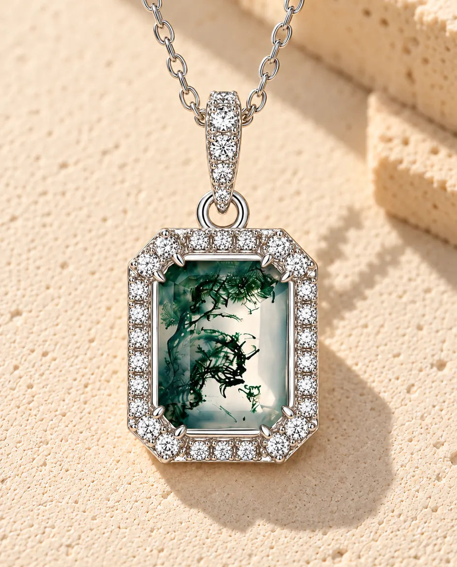 Collar de Ágata Musgosa Talla Esmeralda en Plata 925 - sobre una superficie clara con textura junto a un bloque de travertino