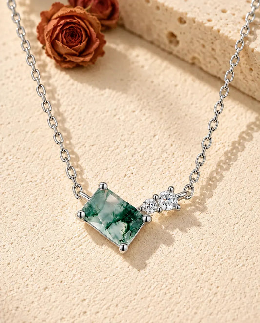Collar de Ágata Musgosa en Plata 925 - sobre una superficie clara con textura junto a un bloque de travertino