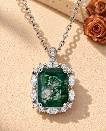 Collar de Ágata Musgosa Talla Esmeralda en Plata 925 - sobre una superficie clara con textura junto a un bloque de travertino