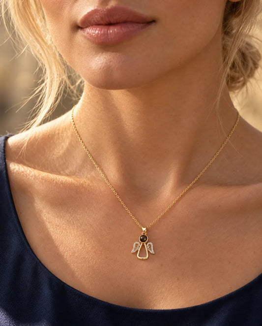 Mujer con un top azul marino que lleva el collar de ángel dorado con foto dentro