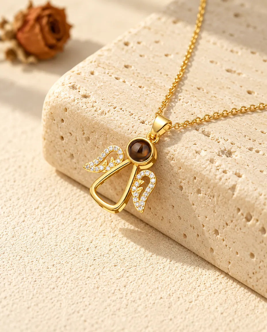 Collar de ángel dorado con foto dentro y alas de circonitas, sobre travertino