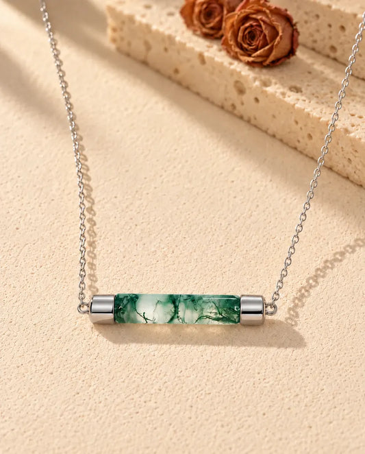 Collar de Barra de Ágata Musgosa en Plata 925 - sobre una superficie clara con textura junto a un bloque de travertino
