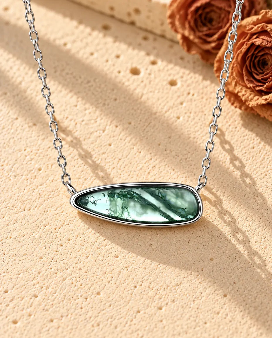 Collar Barra de Ágata Musgosa en Plata 925 - sobre una superficie clara con textura junto a un bloque de travertino