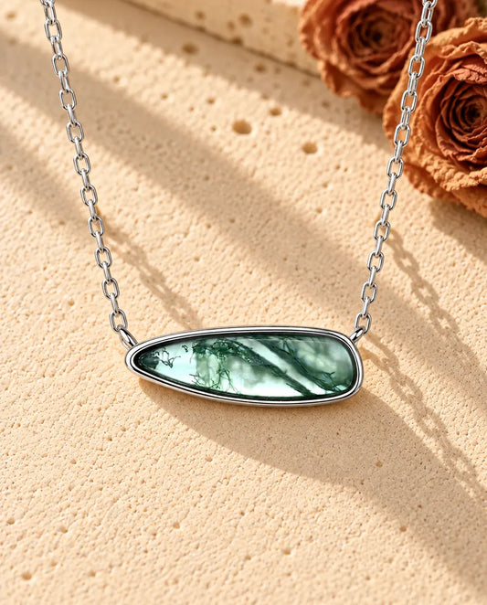Collar Barra de Ágata Musgosa en Plata 925 - sobre una superficie clara con textura junto a un bloque de travertino
