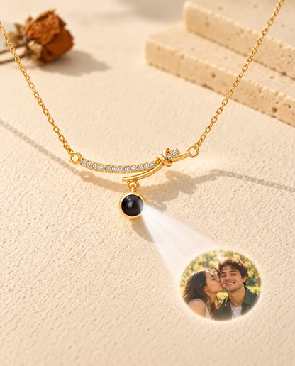 Collar de barra curva dorado que proyecta la foto de una pareja sobre yeso crema