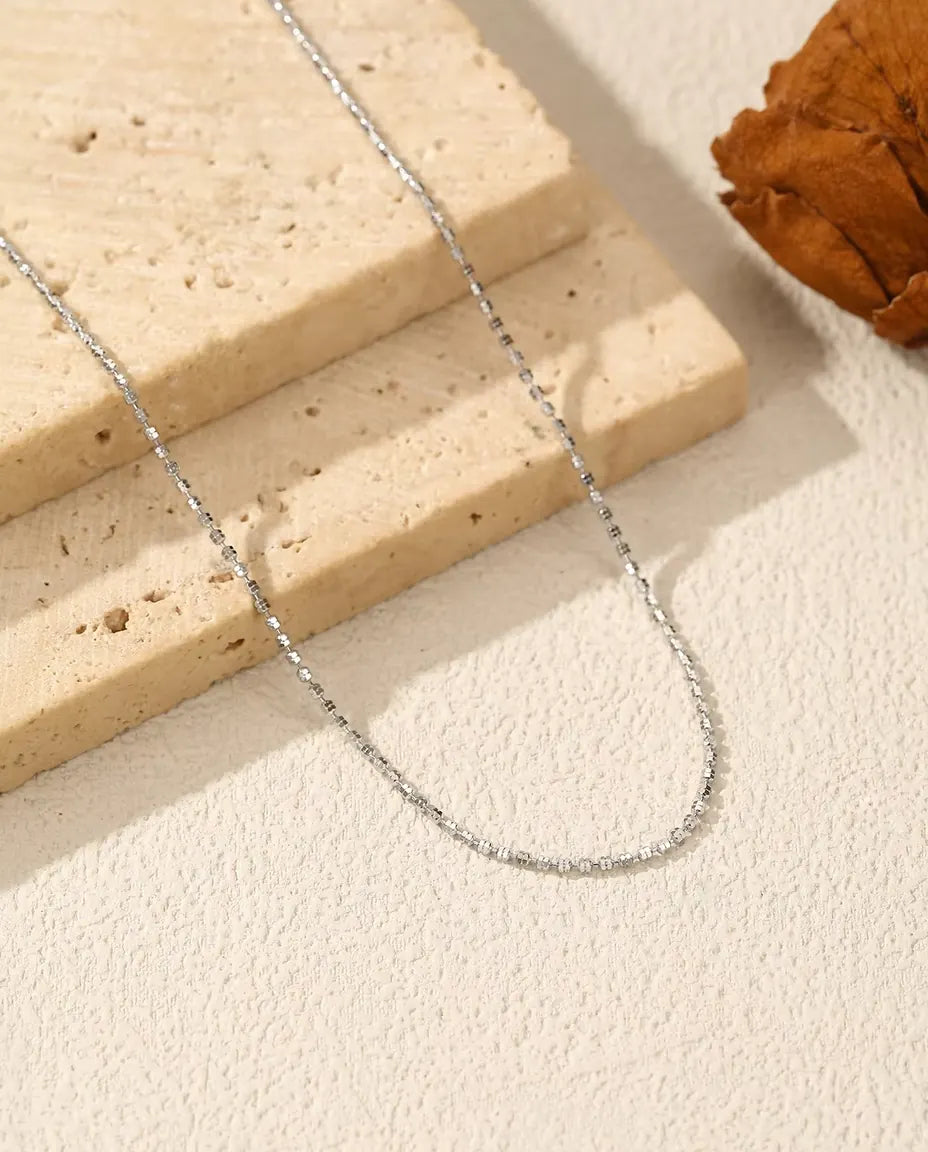 Collar Cadena Diamantada en Plata 925 - sobre una superficie clara junto a una losa de travertino