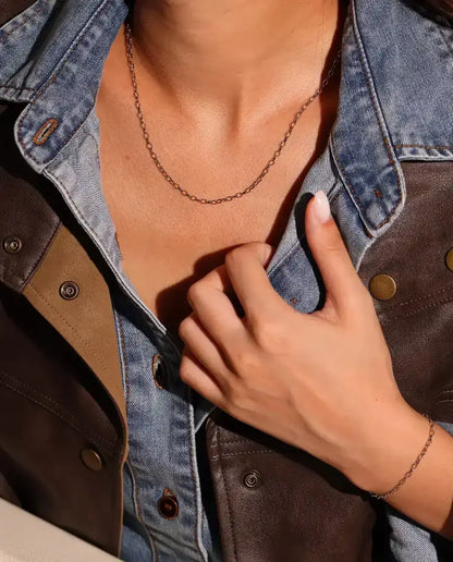 Collar Cadena Forzada en Plata 925 - llevado por una modelo, con la mano en el cuello de la chaqueta