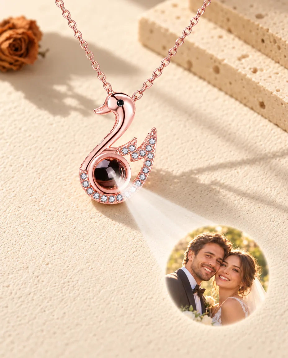 Collar de cisne en color oro rosa cuya bola muestra una foto de boda sobre yeso color crema