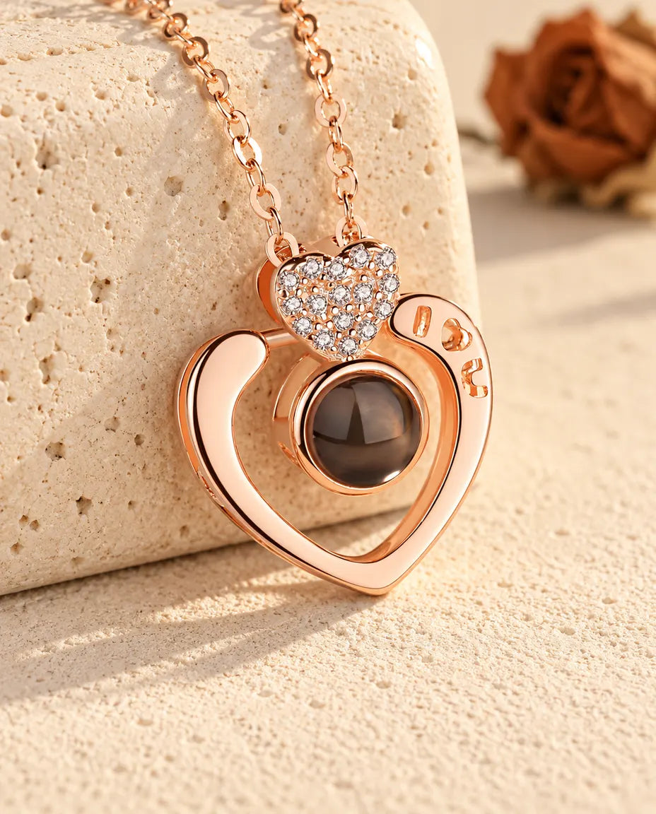 Collar con foto dentro de corazón abierto I love U en color oro rosa, apoyado en un bloque de travertino