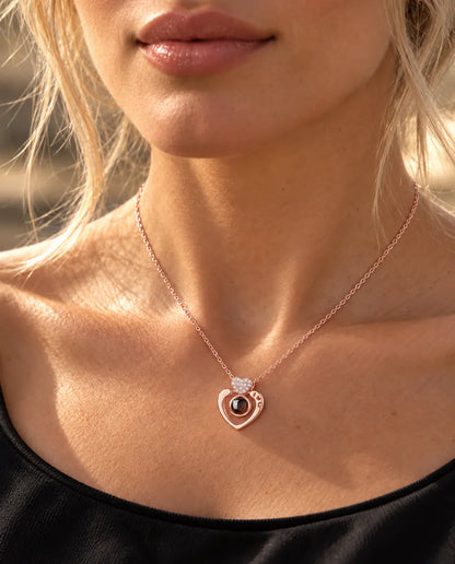 Mujer con un top negro que lleva el collar de corazón abierto en color oro rosa con foto dentro