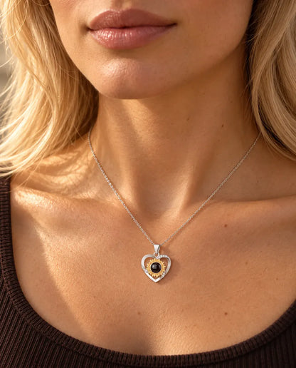 Mujer con un top marrón de punto que lleva el collar de corazón con girasol y foto dentro