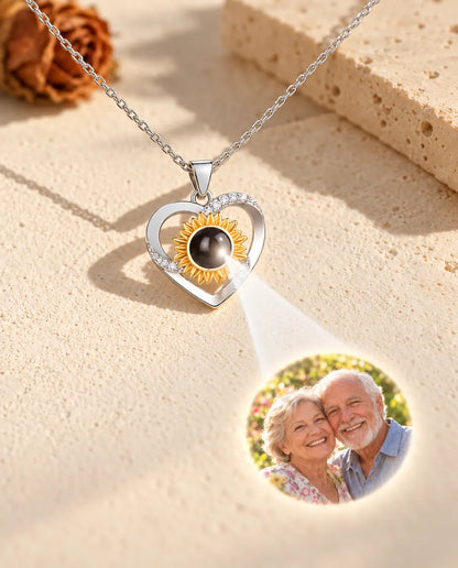 Collar de corazón con girasol cuya bola muestra una foto de unos abuelos sobre yeso color crema