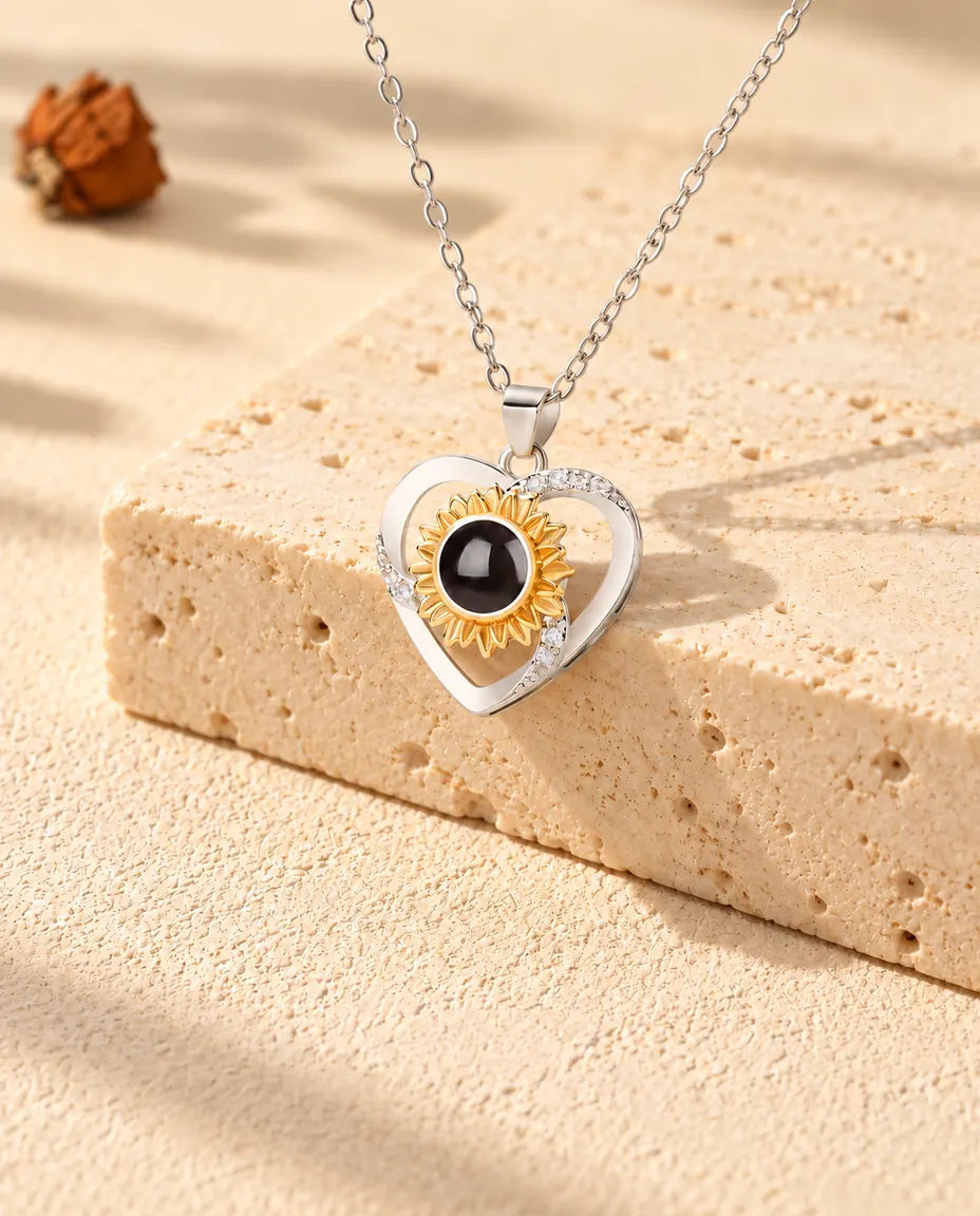 Collar de corazón con girasol y foto dentro, colgado sobre un bloque de travertino