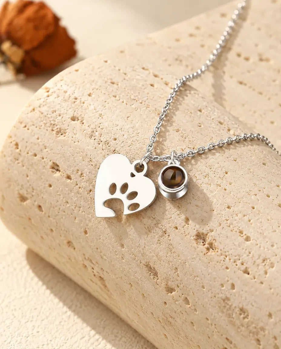Collar plateado con foto de mascota, corazón de huella calada y una bolita de proyección al lado