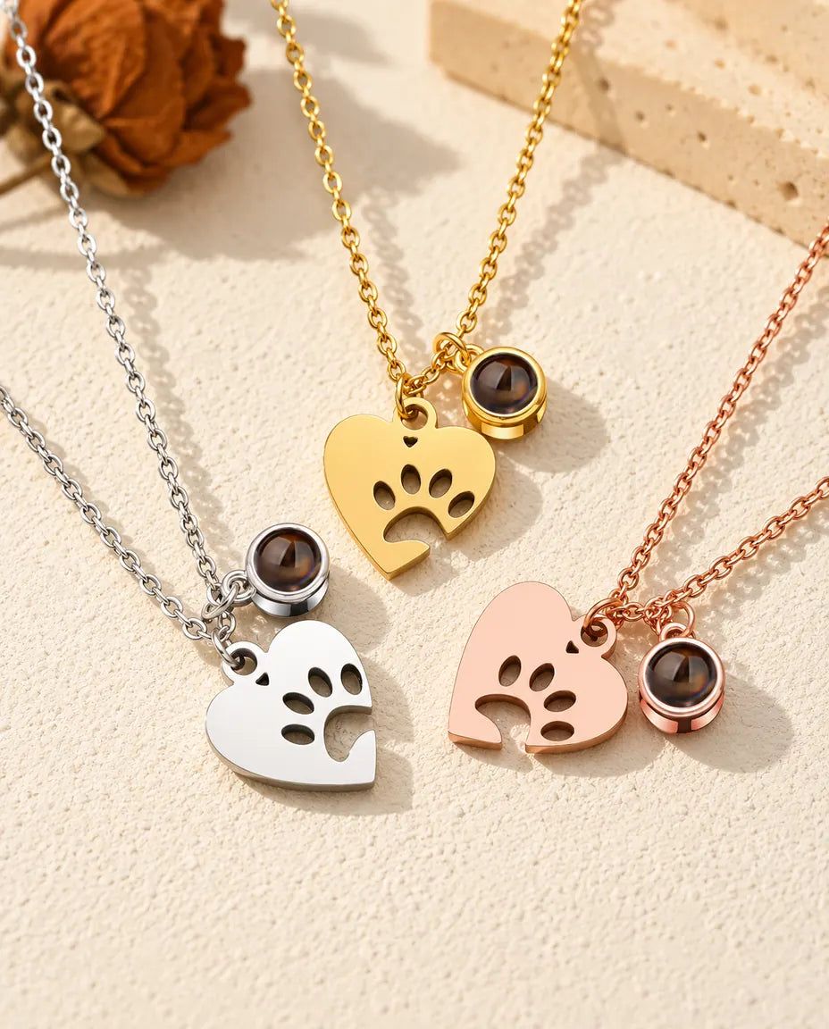 Collares de corazón con huella en plateado, dorado y color oro rosa, cada uno con su bolita de proyección