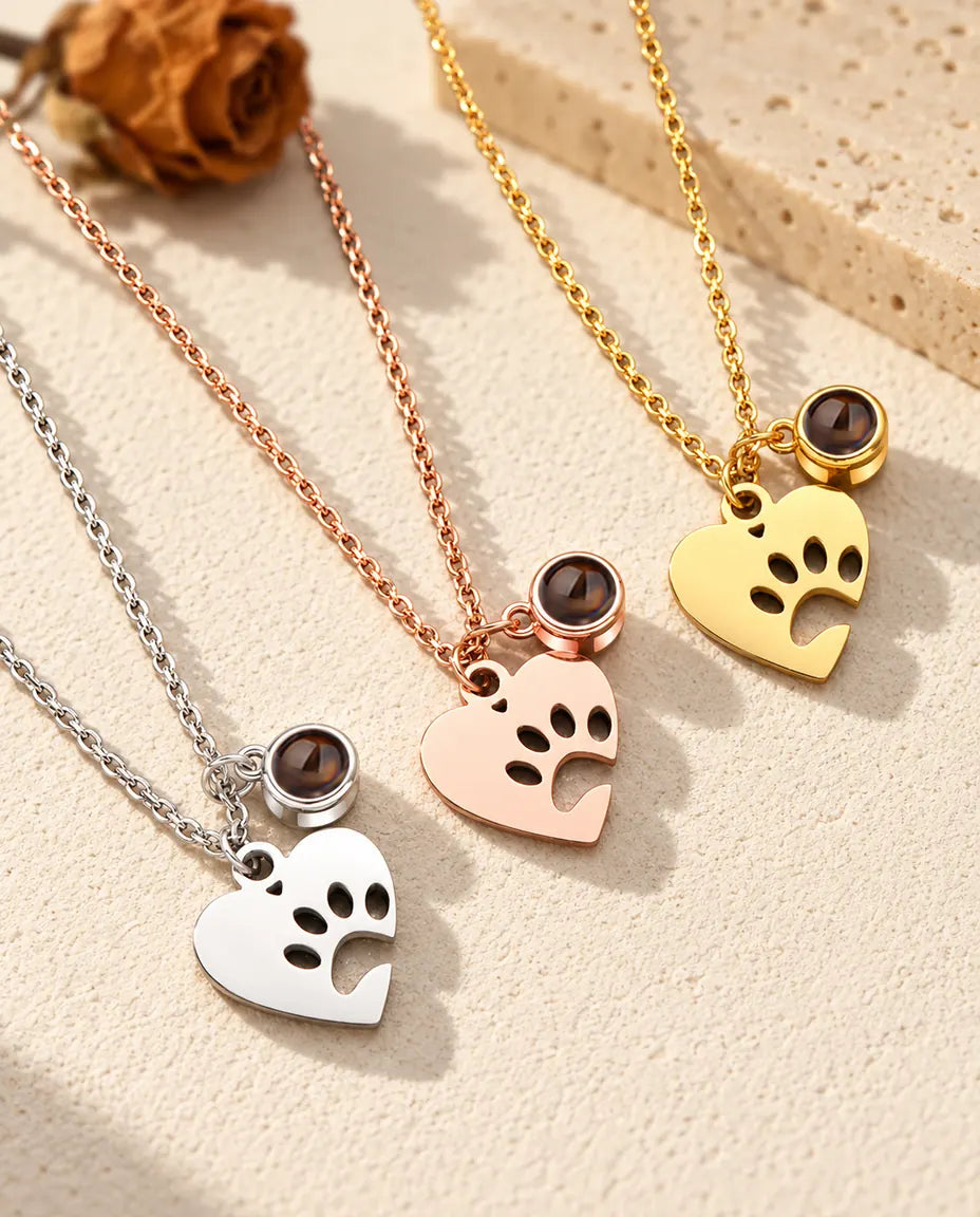 Los tres colores del collar de huella con foto de mascota, en diagonal sobre yeso color crema