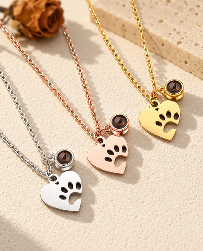 Los tres colores del collar de huella con foto de mascota, en diagonal sobre yeso color crema