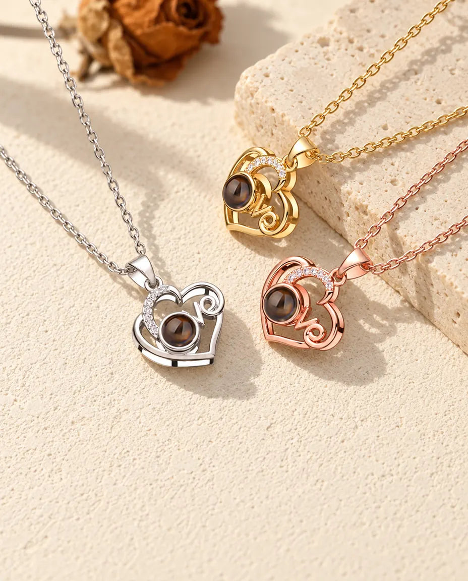 Collares de corazón Love con foto dentro en plateado, dorado y color oro rosa junto a una losa de travertino