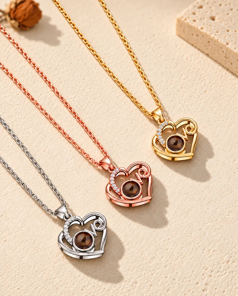Collares Love plateado, color oro rosa y dorado con foto dentro, colocados en diagonal sobre yeso
