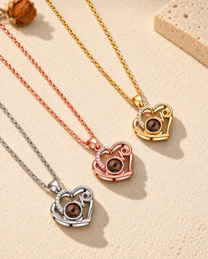 Collares Love plateado, color oro rosa y dorado con foto dentro, colocados en diagonal sobre yeso