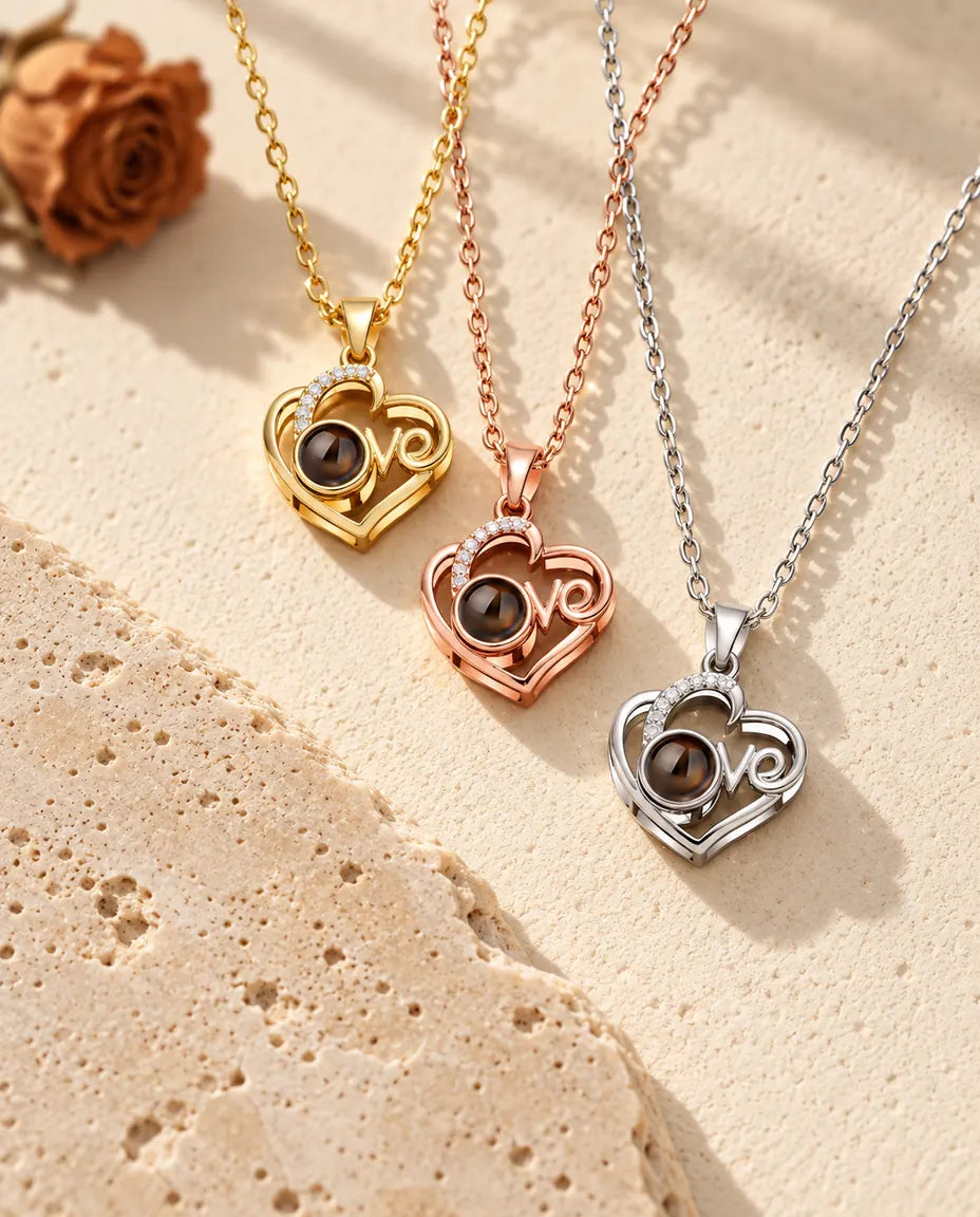 Colgantes de corazón Love dorado, color oro rosa y plateado apilados junto a una losa de travertino