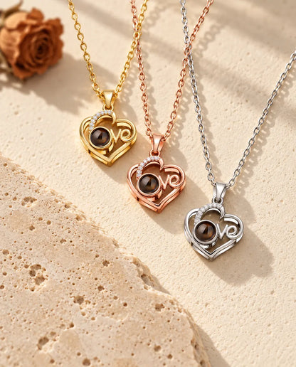 Colgantes de corazón Love dorado, color oro rosa y plateado apilados junto a una losa de travertino