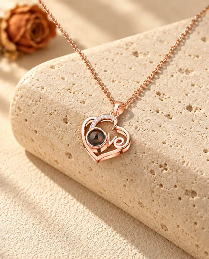 Collar de corazón Love con foto dentro en color oro rosa sobre travertino, con luz cálida de sol