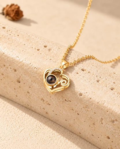 Collar de corazón Love dorado con foto dentro, apoyado en un bloque de travertino