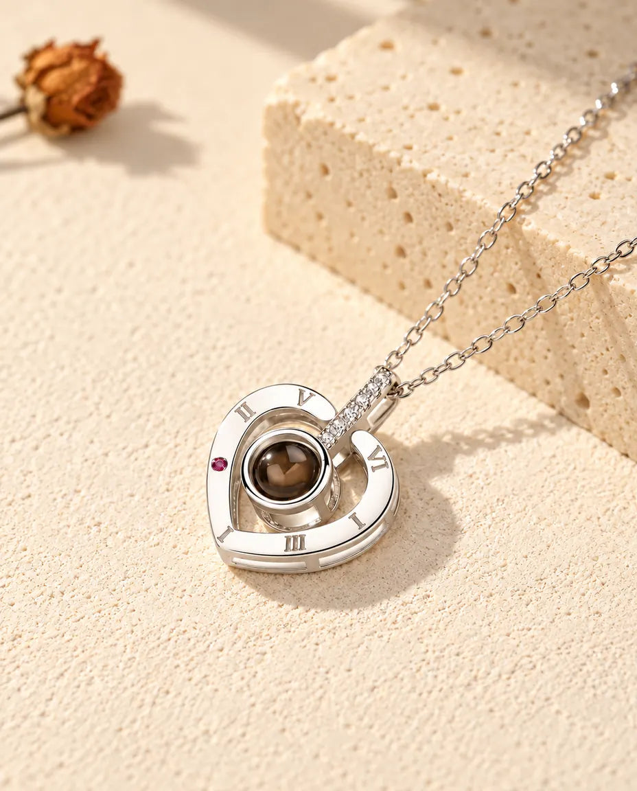 Collar con foto dentro de plata de ley 925 con corazón de números romanos, sobre yeso crema junto a un travertino