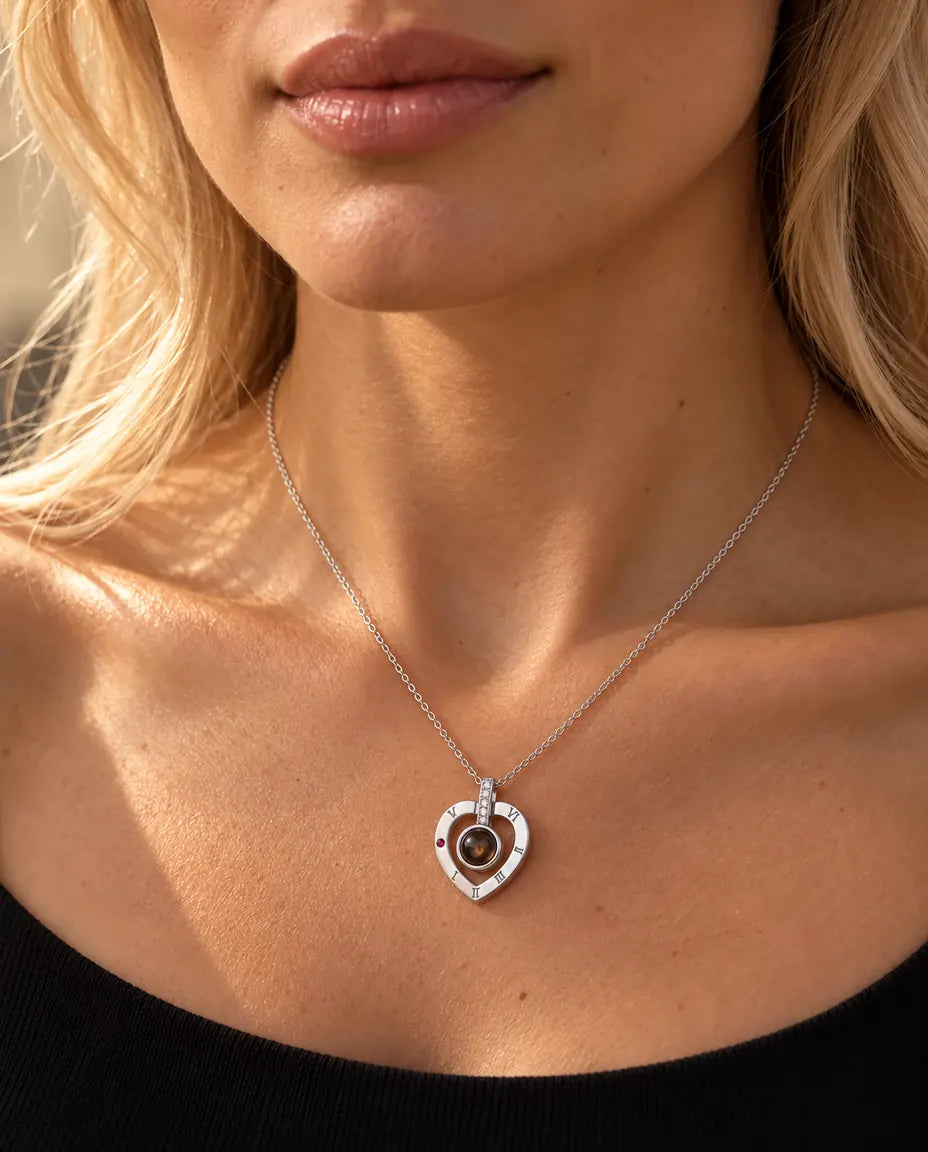 Mujer con un top negro de punto que lleva el collar de plata con corazón de números romanos y foto dentro
